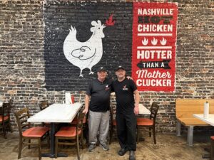 owners of bold bird hot chicken standing in front of a branded mural