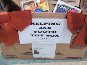 box of toys with sign that says helping jax youth