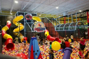 Ball pit with colorful slides and children playing at an indoor amusement center.