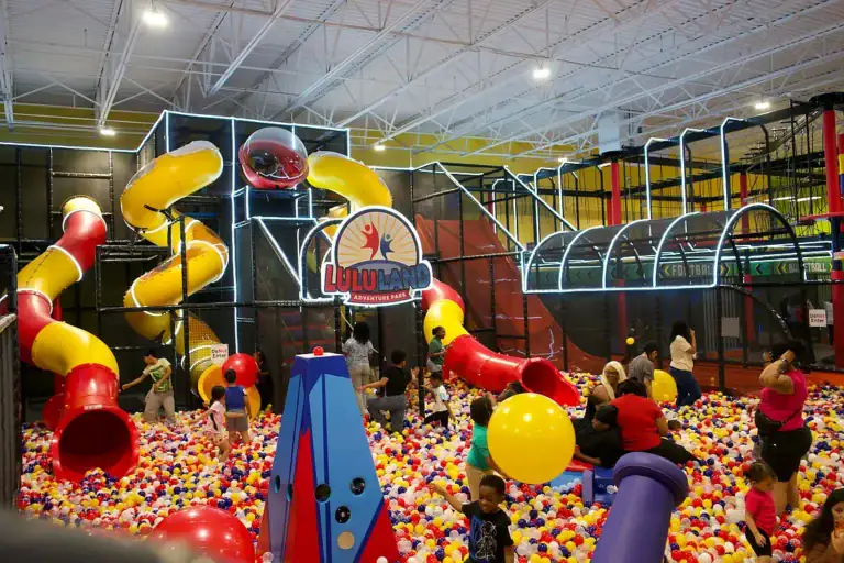 Ball pit with colorful slides and children playing at an indoor amusement center.