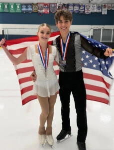 Figure skaters Juliet and Devin Meek holding U.S. flags and medals.