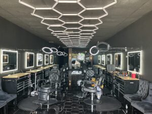 Modern barbershop interior with illuminated mirrors and styling chairs.